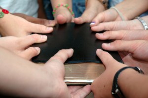 A youth group holds on to a bible.